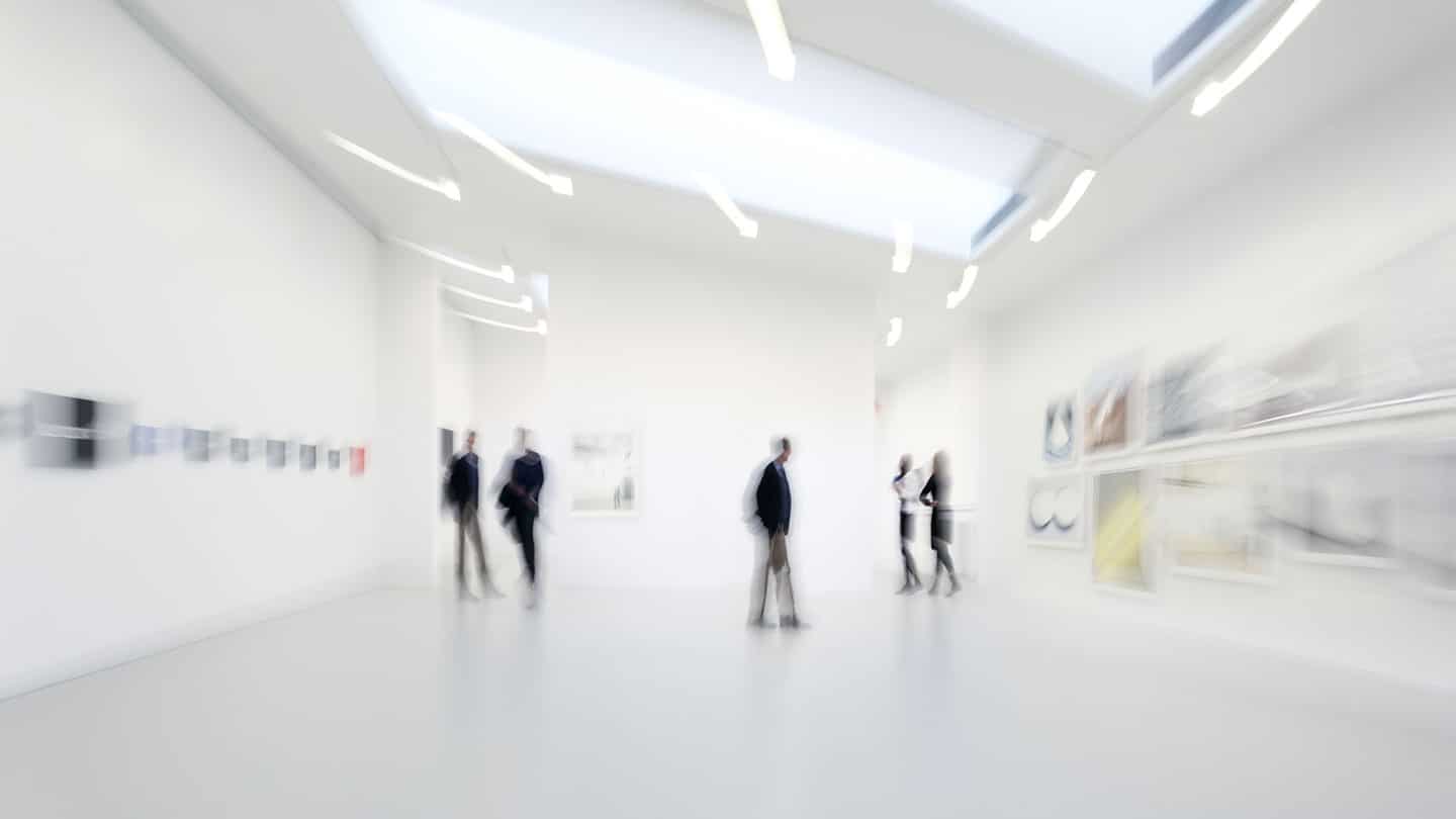 blurred image of people walking around an art gallery