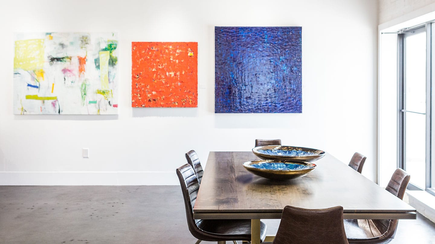 three pieces of artwork on a wall with a table in the foreground