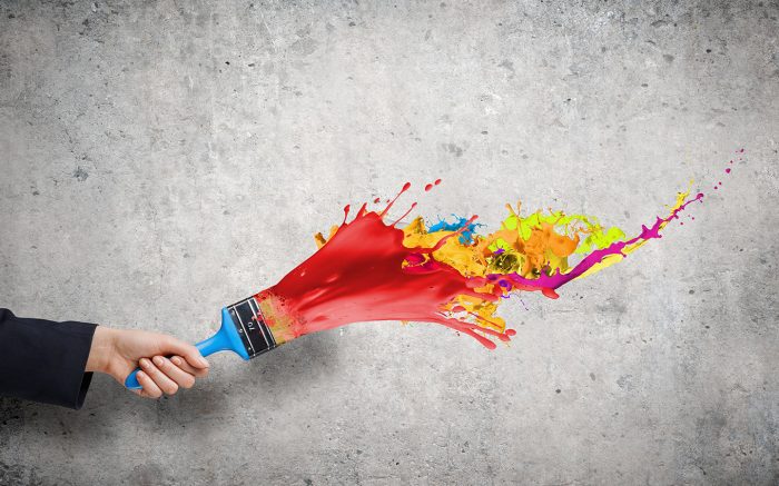 man in suit splashing colourful pain on a wall